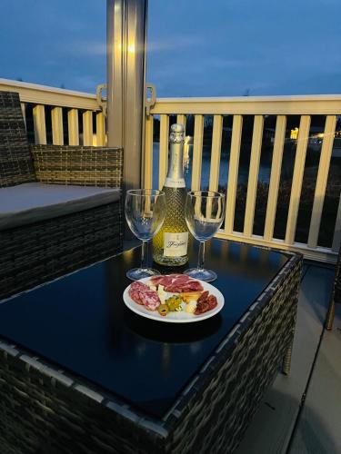 a table with a plate of food and two wine glasses at Lakeside Escape with Hot Tub in York