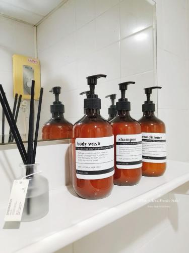 four bottles of soap on a shelf in a bathroom at White Cloud Family Suite in Ban Kohong