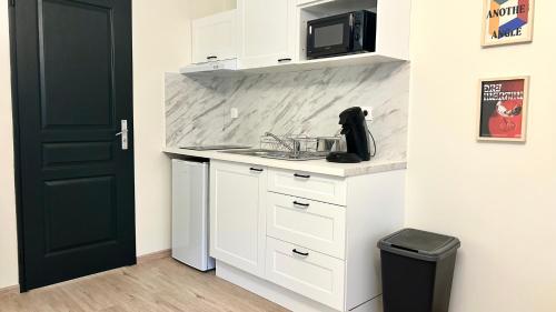 une cuisine blanche avec un évier et un micro-ondes dans l'établissement L'atmosphère, à Nevers