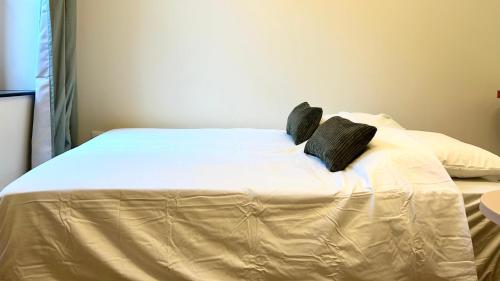 - un lit avec des draps blancs et des oreillers noirs dans l'établissement L'atmosphère, à Nevers