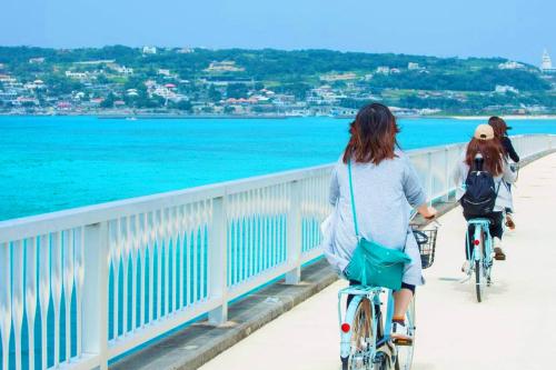 two people riding bikes on a bridge over the water at 【KouriGarden】古宇利島の海と緑と星を眺める一棟貸切別荘ヴィラ in Nakijin