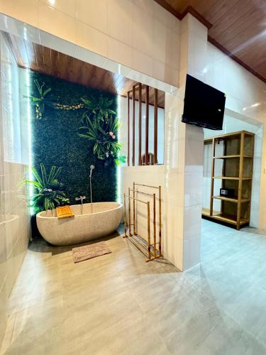a bathroom with a tub with plants on the wall at Ayu Homestay in Ubud