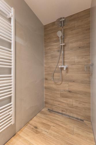 a shower in a bathroom with a wooden wall at Apartmány Dominek in Ždiar
