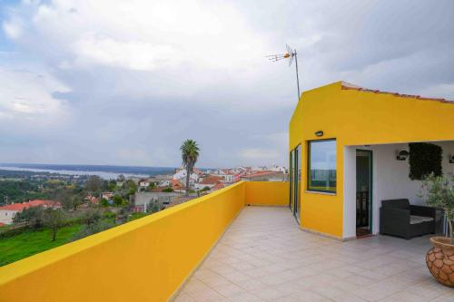 a yellow and white house with a yellow balcony at Lake View House _ Montargil in Montargil