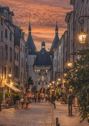 a group of people walking down a city street at sunset at Petit cocon proche de Stanislas in Nancy