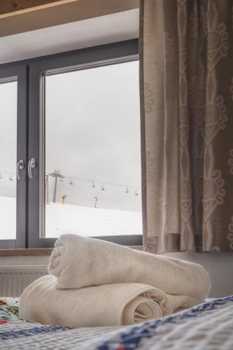 a towel sitting on a bed in front of a window at Apartmány Dominek in Ždiar