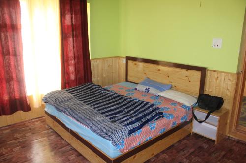 a bedroom with a bed with a wooden head board at Kunjung palter home stay in Kaza