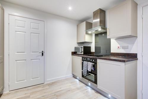 a kitchen with white cabinets and a white door at Entire house in Stanway, Colchester in Colchester