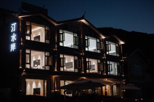 a lit up building with an umbrella in front of it at Lakeside Retreat - LuguLake Lijiang in Zuosuo