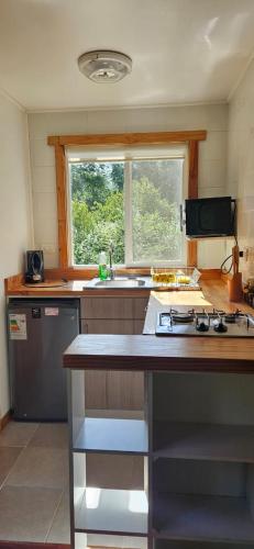 Una cocina con estufa, fregadero y ventana. en Refugio Lefun, en Molco