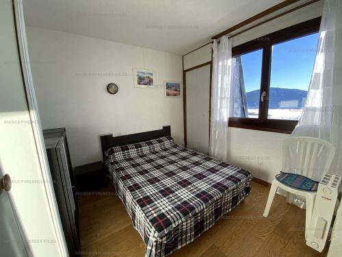 une chambre avec un lit, une fenêtre et une chaise dans l'établissement T2 4 personnes avec parking et casier à skis à 300m des commerces - FR-1-295-169, aux Angles
