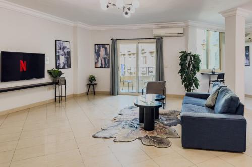 a living room with a blue couch and a tv at Distinct & Decent 2 BDR Apt Steps From Nightlife and Airport in Cairo