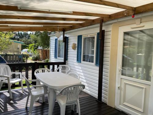 a patio with a table and chairs on a deck at Mobilhome Super Titania - 3 Bedrooms - Family Camping JF102 in Les Mathes