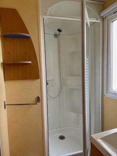 une douche avec une porte vitrée dans une salle de bain dans l'établissement Mobilhome Super Titania - 3 Bedrooms - Family Camping JF102, aux Mathes