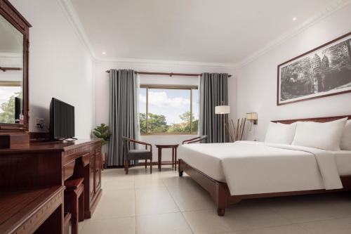 a bedroom with a bed and a desk and a table at Baitong Heritage Hotel in Siem Reap