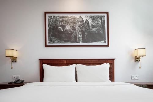 a bedroom with a bed with a picture on the wall at Baitong Heritage Hotel in Siem Reap