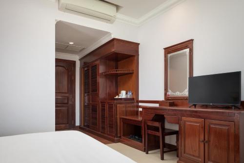 a bedroom with a desk with a television and a mirror at Baitong Heritage Hotel in Siem Reap