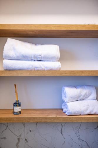 two white towels on a wooden shelf in a bathroom at Stylish Apartment Otopeni in Otopeni