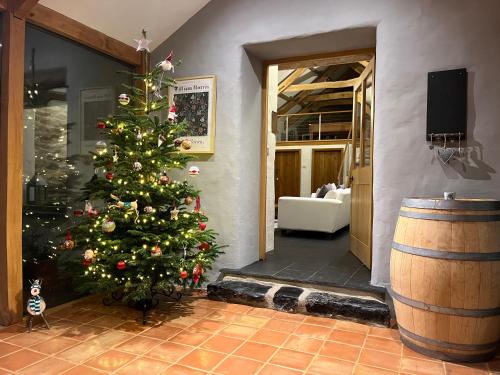 a christmas tree in a room with a barrel at Dan y Graig Barn, Carmarthen in Carmarthen