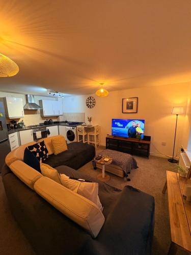 a living room with a couch and a flat screen tv at 2 bedroom 2 bathroom ground floor apartment in central location in Warrington