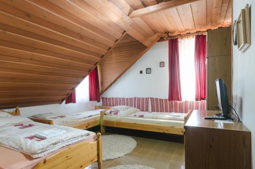 a room with two beds and a desk and a television at Família Panzió in Pannonhalma