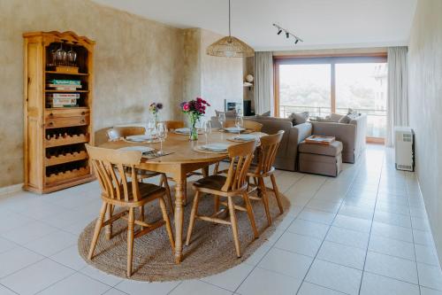 a dining room table and chairs in a living room at Prachtig, rustig en ruim appartement vlakbij zee in Koksijde