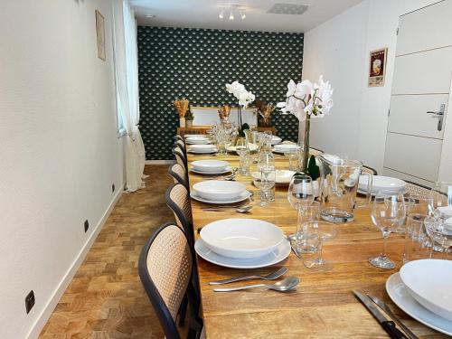 - une grande table avec des assiettes et des verres blancs dans l'établissement Maison Auseths - Gîte de groupe - Campan, à Campan