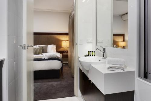a bathroom with a white sink and a large mirror at Attika Hotel in Perth