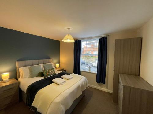ein Schlafzimmer mit einem großen Bett und einem Fenster in der Unterkunft Barroon Castle Apartments - Next to East Midlands Airport with Free Parking in Castle Donington