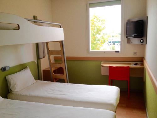 a bedroom with a bunk bed and a desk with a red chair at Ibis Budget Roanne Hôtel in Roanne
