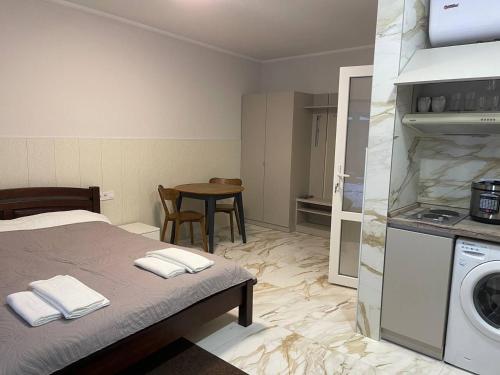 a room with a bed and a kitchen with a washing machine at Апартаменти в центрі міста in Poltava
