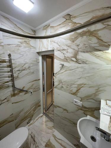 a bathroom with a marble wall with a toilet and a sink at Апартаменти в центрі міста in Poltava