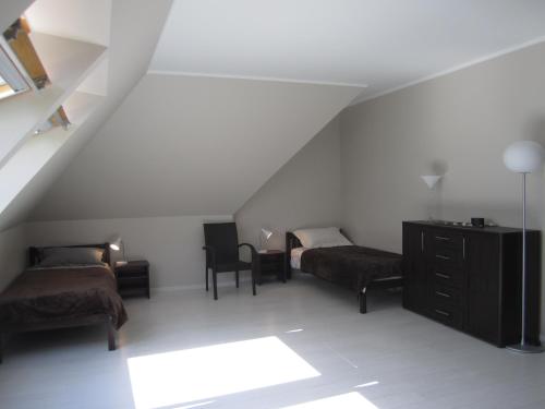 a attic room with two beds and a dresser at Jaunkrastmaļi in Kandava
