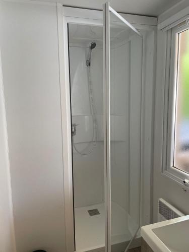 une douche avec une porte vitrée dans une salle de bain dans l'établissement Quiet mobile home - 3 Bedrooms - Family Camping JF402, aux Mathes