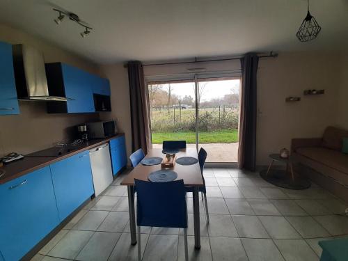 a kitchen with blue cabinets and a table with a tablektop at Quartier des peintres - Poussin in Chaveignes