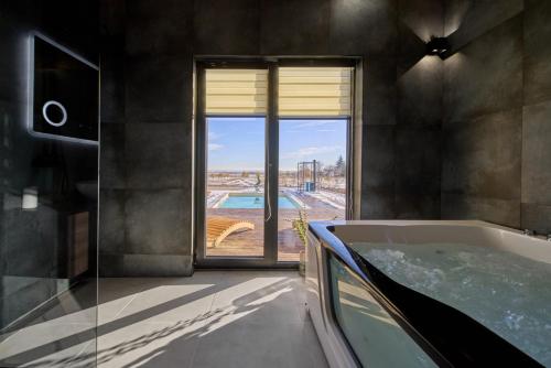 a bathroom with a tub with a view of a pool at Casa del Corniolo in Čortanovci