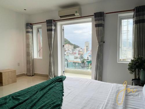 a bedroom with a bed and a large window at Joi Hospitality - Anthony in Vung Tau