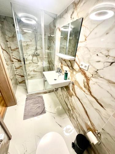 a marble bathroom with a sink and a shower at Pension Hirsch in Berg