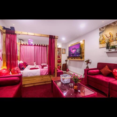 a living room with a red couch and a bed at Pink Hawk Hospitality in Hyderabad