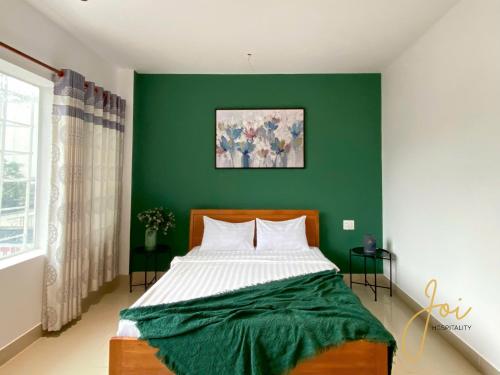 a bedroom with a green wall and a bed at Joi Hospitality - Anthony in Vung Tau