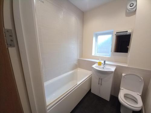 a bathroom with a toilet and a tub and a sink at Cosy Spacious 2 bedroom Apartment Free Parking in Nottingham