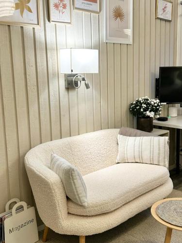a living room with a white couch and a lamp at Lilla huset Bed & Breakfast - countryside guesthouse, free parking in Örebro