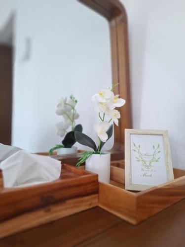 a wooden tray with a picture and flowers in a mirror at Alzena villa batu in Batu