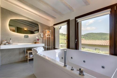 a bathroom with a large tub and a large mirror at Amore Rentals - Ville Il Paradiso in Panzano