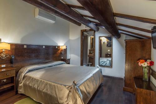 Schlafzimmer mit einem großen Bett mit einem Kopfteil aus Holz in der Unterkunft Al Casaletto Hotel in Settecamini