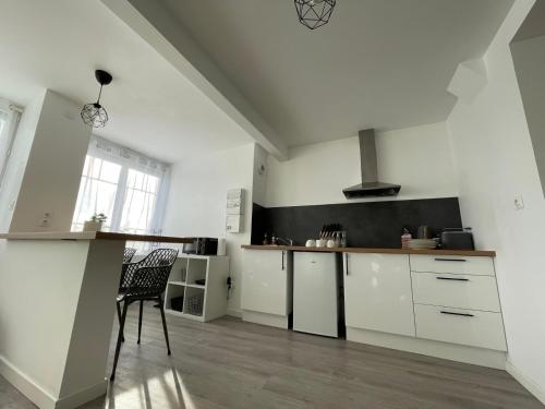 - une cuisine avec des placards blancs et une chaise dans l'établissement Appartement moderne, à Montrichard