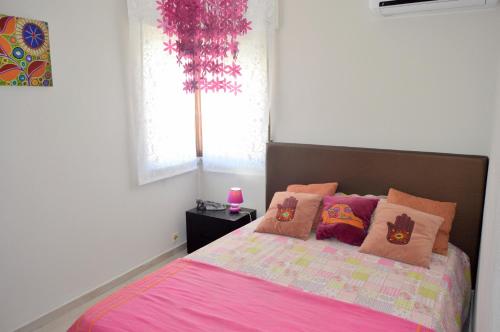 a bedroom with a pink bed with pillows and a window at Manta Rota Beach Haven in Vila Nova De Cacela