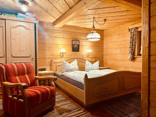 a bedroom with a bed and a chair at Almbrünnerl die Almhütte auf der Raffner Alm in Ruhpolding