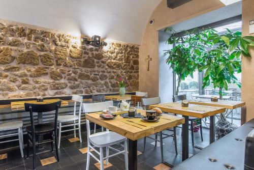 a restaurant with wooden tables and chairs and a stone wall at Al Casaletto Hotel in Settecamini
