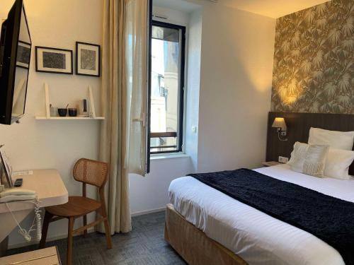 a bedroom with a bed and a desk and a window at Cit'Hotel Hôtel de France et d'Europe in Concarneau